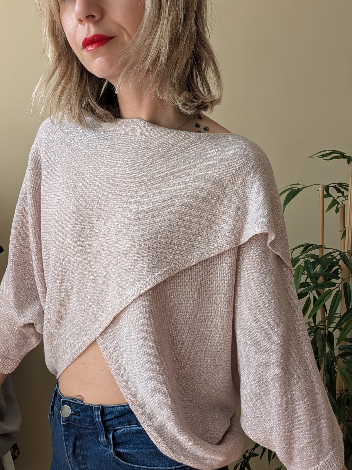 Detalle del escote asimétrico de la blusa beige