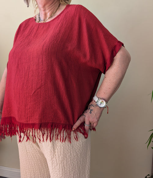 Blusa granate de corte amplio con manga corta y flecos en el bajo
