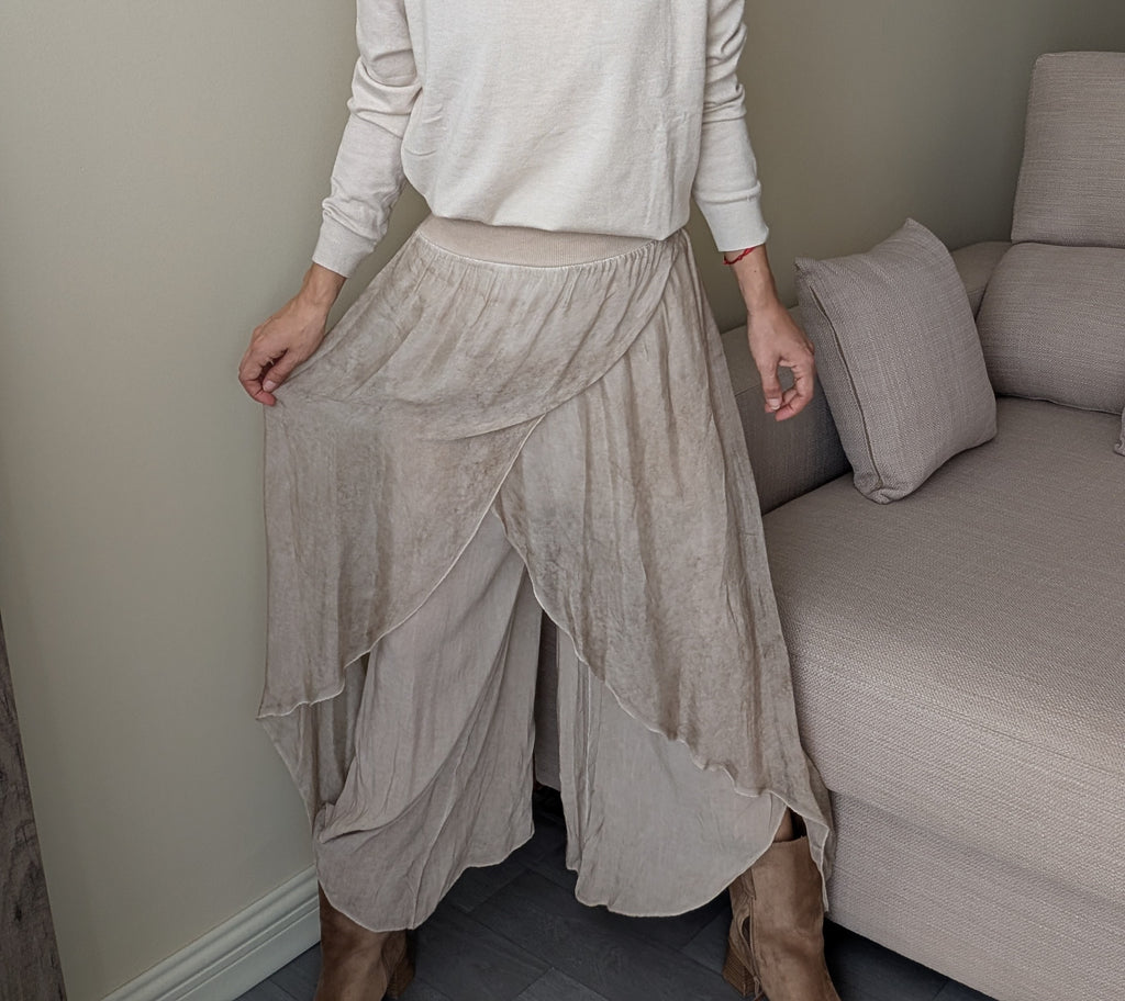 Pantalón beige de capas asimétricas, detalle frontal de cintura y tejidos superpuestos