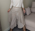 Pantalón beige de capas asimétricas, detalle frontal de cintura y tejidos superpuestos