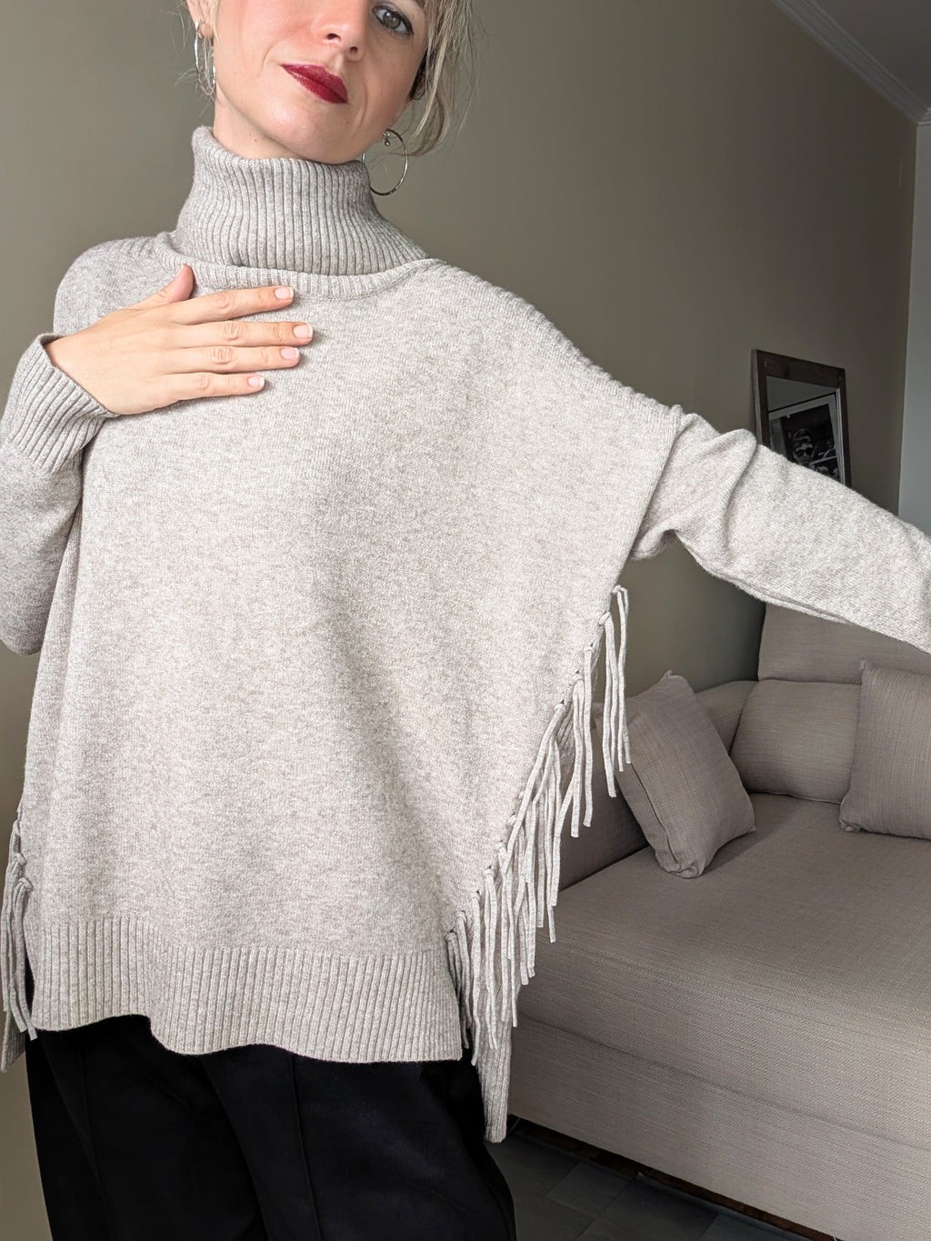 Detalle del cuello alto, punto y flecos laterales del jersey de mujer.