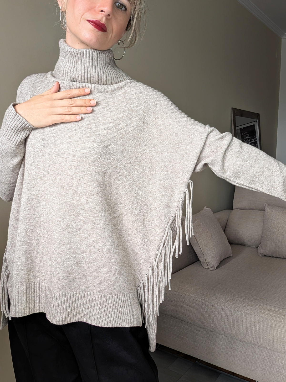 Detalle del cuello alto, punto y flecos laterales del jersey de mujer.