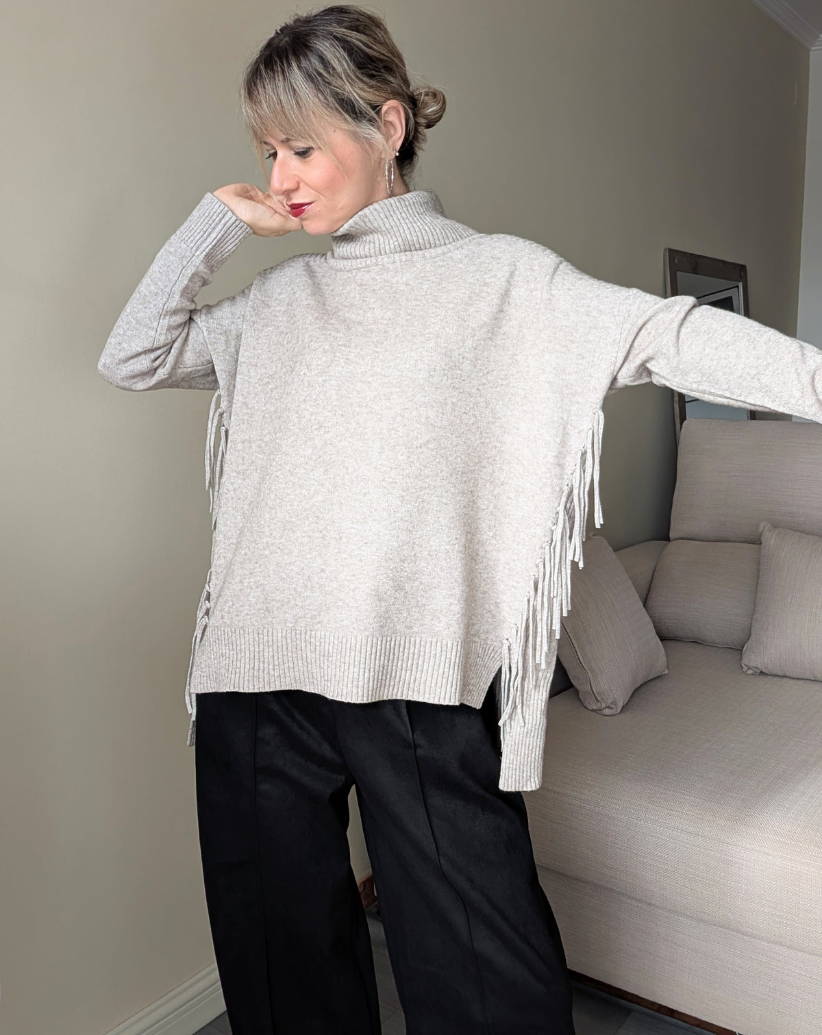 Vista frontal del jersey de cuello alto con flecos laterales y corte amplio.