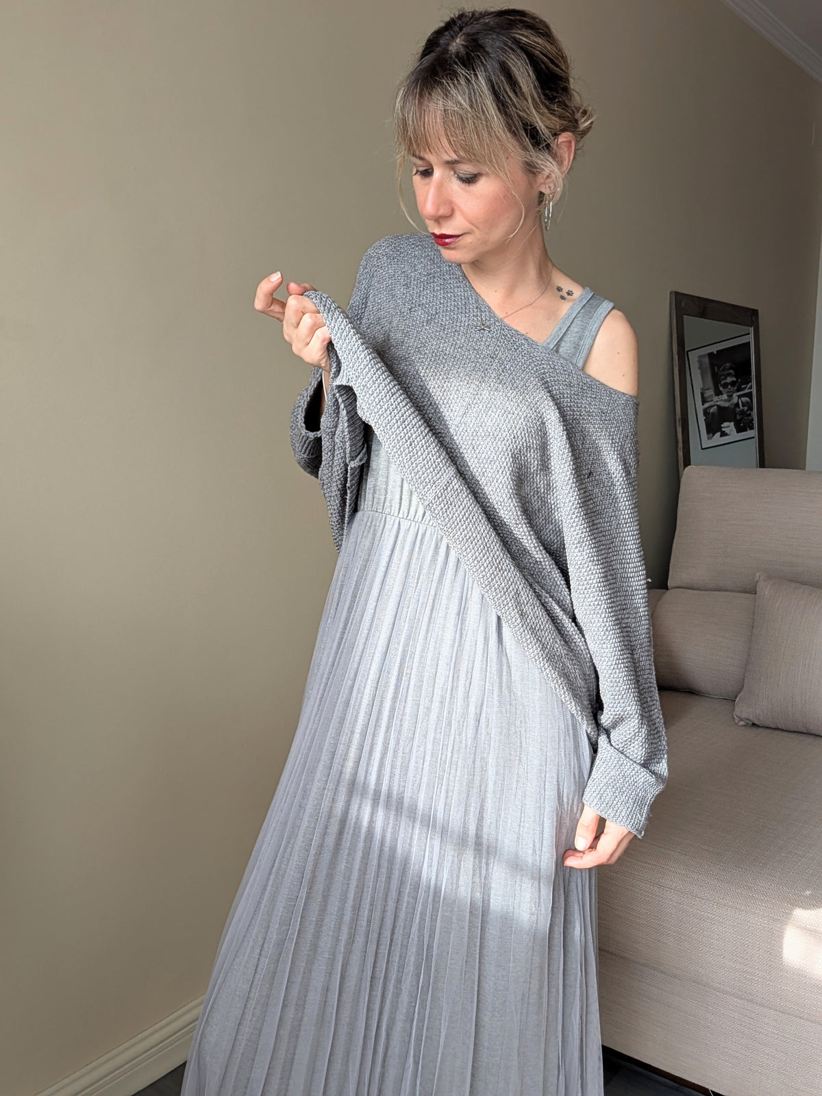 Jersey gris levantado para mostrar el vestido independiente que lleva debajo.