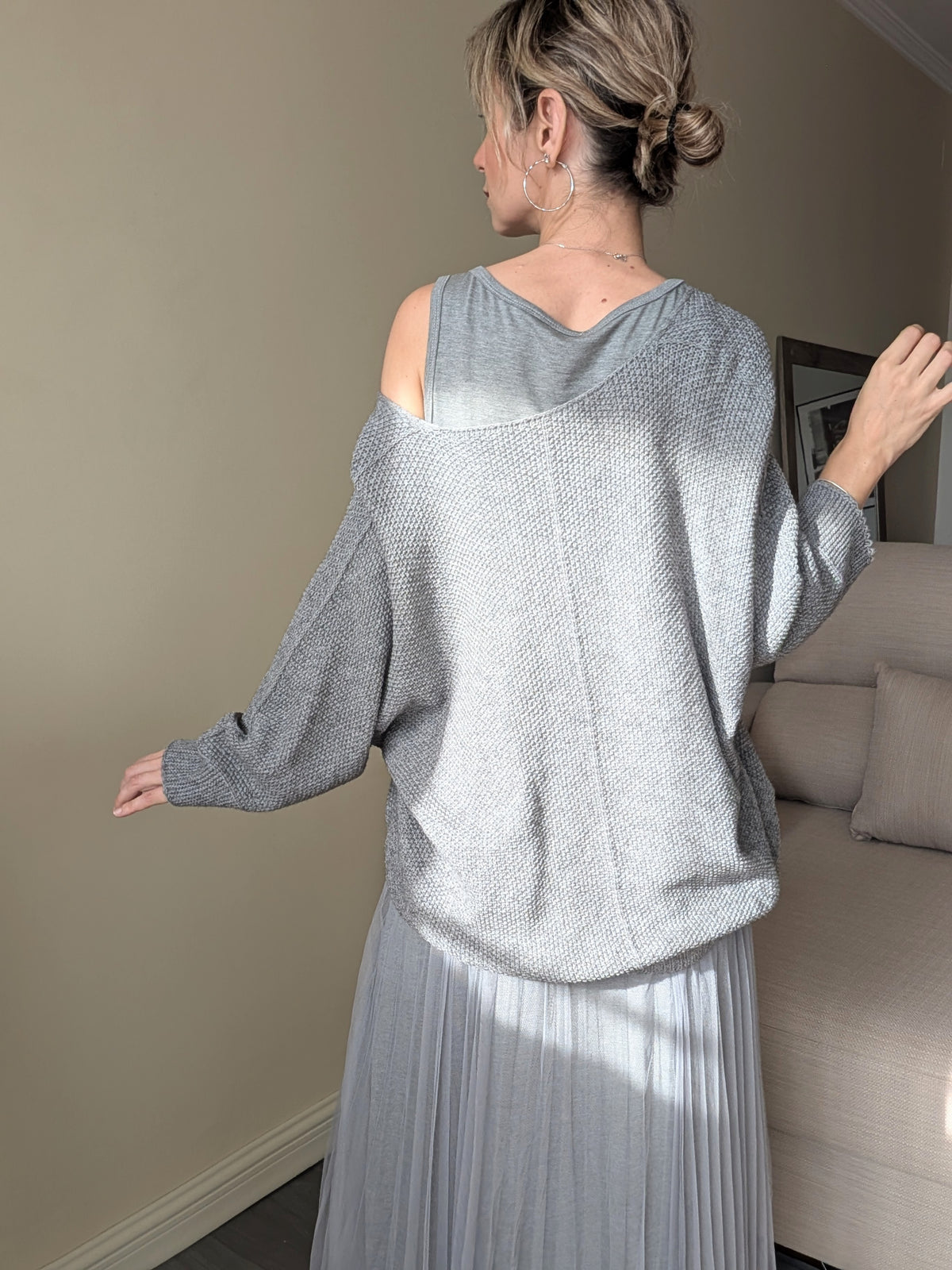 Vista trasera del conjunto gris con jersey de punto y falda plisada del vestido.