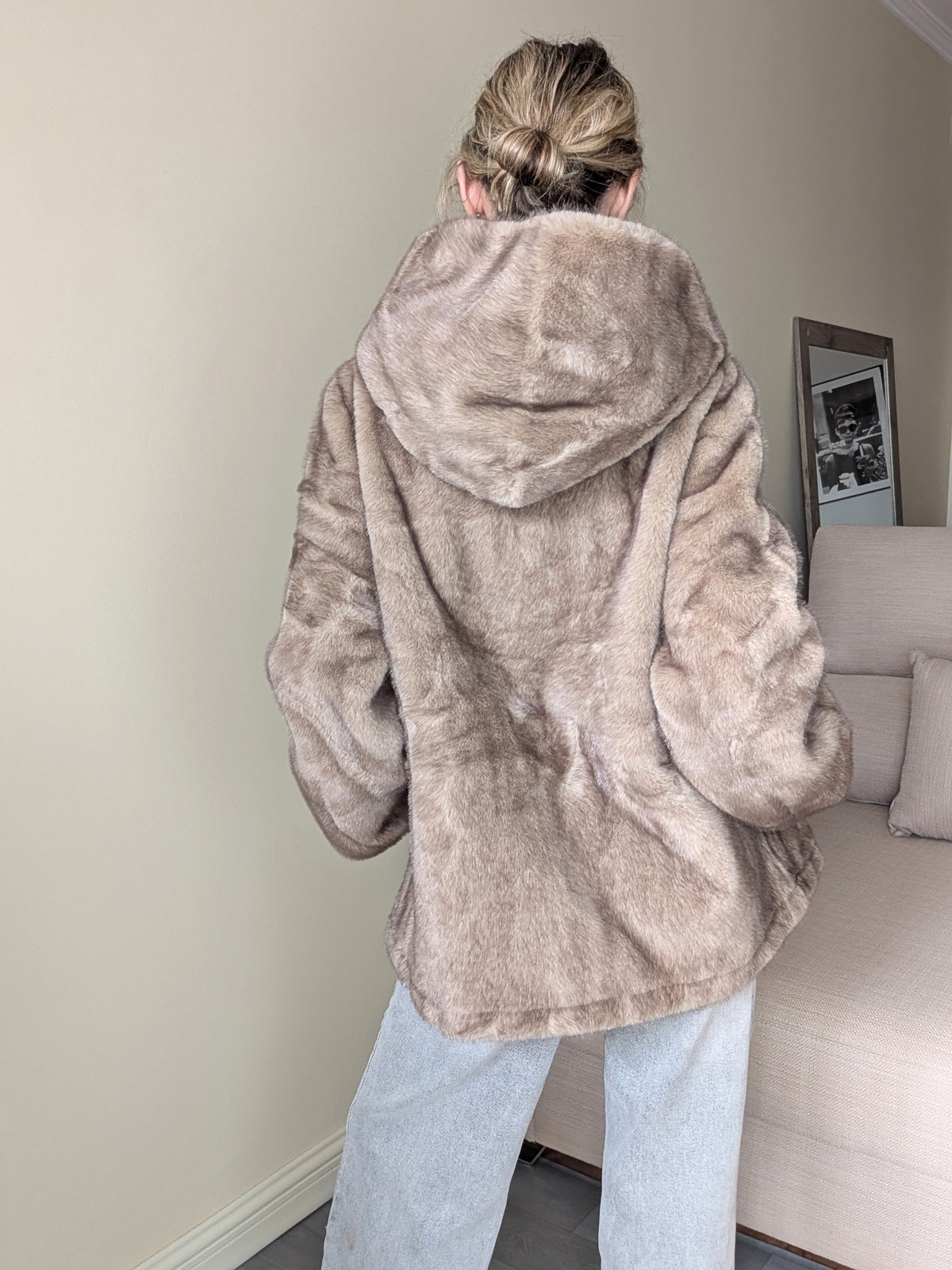 Espalda del abrigo de pelo sintético topo con capucha.