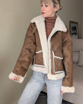 Chaqueta marrón abierta con cuello y ribetes de pelo crudo, vista frontal.
