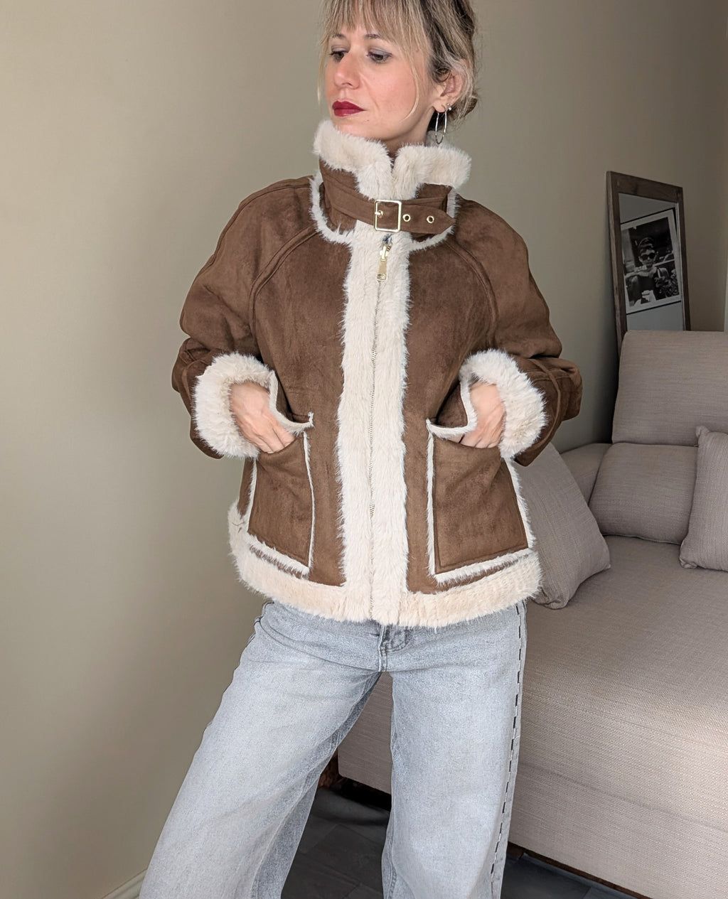 Chaqueta marrón cerrada con hebilla en el cuello y bolsillos exteriores.