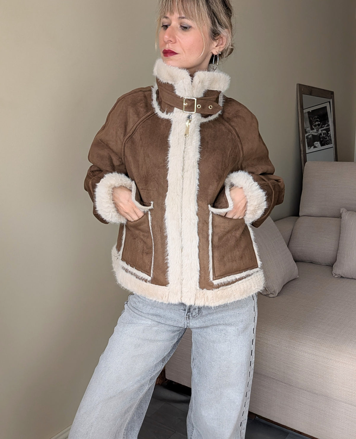 Chaqueta marrón cerrada con hebilla en el cuello y bolsillos exteriores.