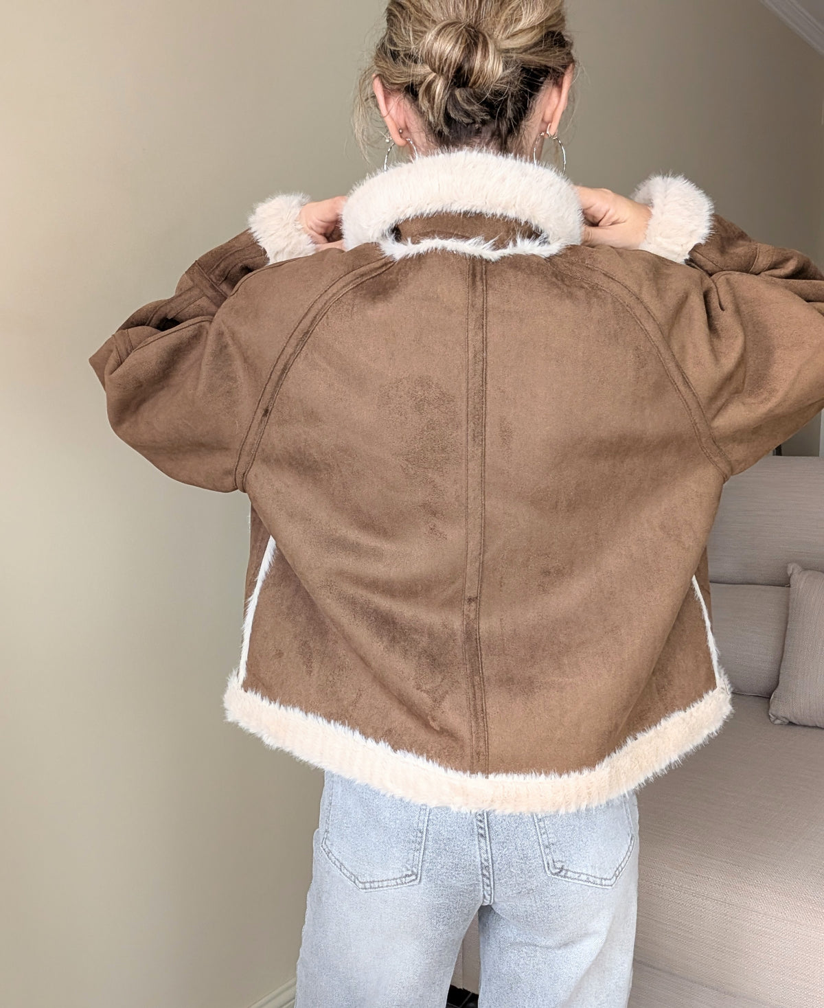 Espalda de la chaqueta marrón con costura central y cuello de pelo crudo.