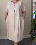 Vestido midi beige de corte amplio con manga corta y bolsillos laterales